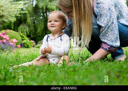 Mutter mit Babymädchen sitzen auf dem Rasen Stockfoto