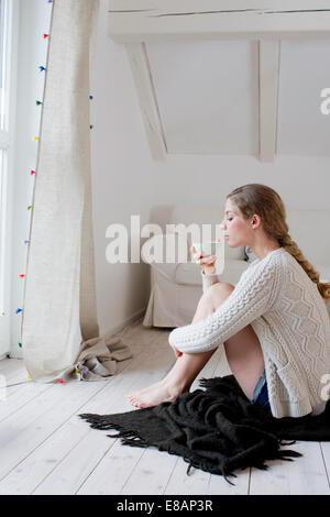 Frau sitzt auf Etage Tee trinken Stockfoto