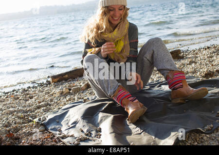 Frau sitzt auf windiger Strand Stockfoto