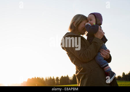 Reife Mutter und Baby Tochter im Feld bei Sonnenuntergang Stockfoto