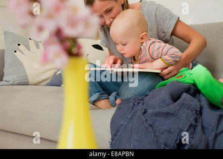 Reife Mutter Baby Tochter auf Wohnzimmer Sofa lesen Stockfoto