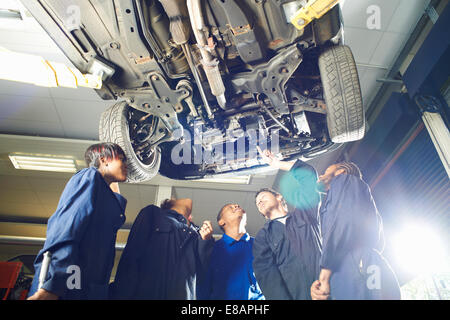 Fünf Studenten nachschlagen unter Auto in Garage Werkstatt Stockfoto