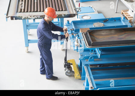 Arbeiter mit manuellen Hubwagen in Industrieanlagen Stockfoto