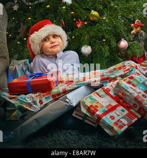 Porträt des netten jungen sitzen auf Boden mit Weihnachten präsentiert auf ihn Stockfoto