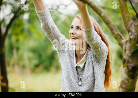 Junge Frau im Feld festhalten an Ast Stockfoto