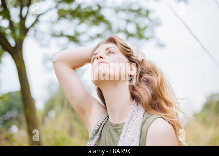 Ruhige junge Frau blickte mit Hand im Haar Stockfoto