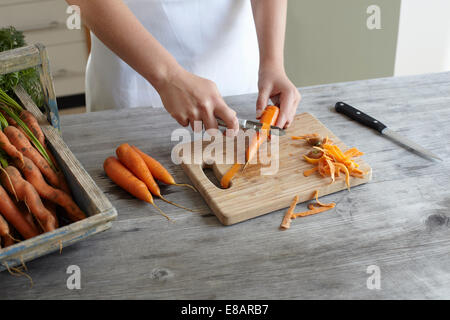 Händen des Mädchens schälen Möhren auf Küchentisch Stockfoto