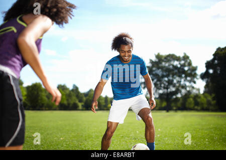 Junges Paar Fußball spielen zusammen im park Stockfoto