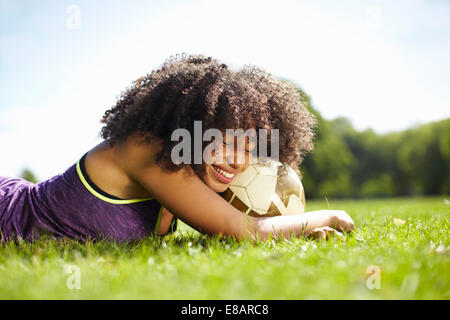 Junge Frau, die eine Pause im Park stützte sich auf Fußball Stockfoto