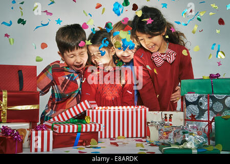 Brüder und Schwestern Auspacken leuchtende Weihnachts-Geschenk-Box mit explodierenden Konfetti überrascht Stockfoto