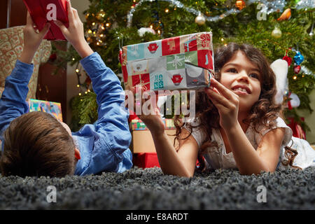 Schwester und Bruder im Wohnzimmer hält Weihnachtsgeschenke liegen Stockfoto