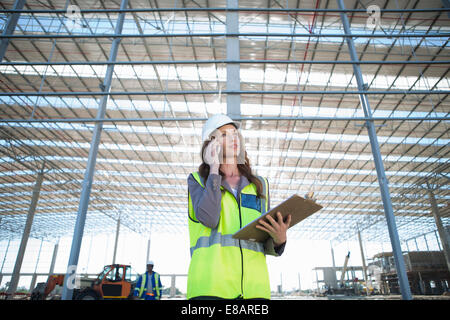 Bauleiter mit Zwischenablage im Chat auf Smartphone auf Baustelle Stockfoto