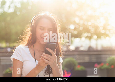 Junge Frau mit Kopfhörern Musik hören Stockfoto