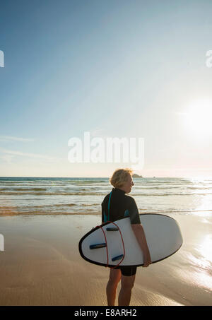 Senior Surferin stehen am Strand mit Surfbrett, Camaret-Sur-Mer, Bretagne, Frankreich Stockfoto