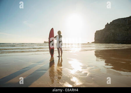 Silhouette senior Frau stehen am Strand mit Surfbrett, Camaret-Sur-Mer, Bretagne, Frankreich Stockfoto