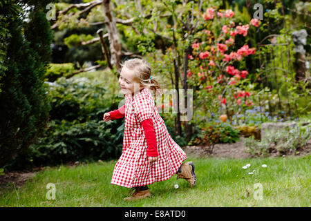 Junge Mädchen tragen karierte Kleid im Garten laufen Stockfoto