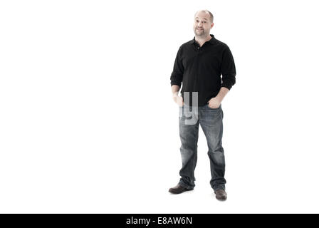 Voller Länge erschossen von einem Mann stehend mit den Händen in den Hosentaschen, schaut in die Kamera und lächelnd Schuss auf weißem Hintergrund Stockfoto