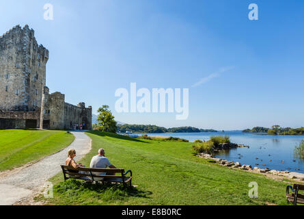 Paar auf Bank vor Ross Castle am Ufer des Lough Lean, Killarney Nationalpark, County Kerry, Irland Stockfoto