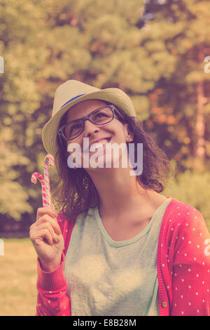 Glücklich Hipster teenage Girl Thinking of Sweets und Zuckerstangen halten. im Freien Schuss, Retro-Farben Stockfoto