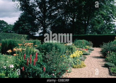 Roten Lupinen und orange Hemerocallis in breiten krautige Grenze neben Kiesweg im großen Bauerngarten im Sommer Stockfoto