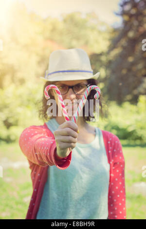 Glückliches Hipster Teenager Mädchen zeigt Zuckerstangen. im Freien Schuss, Retro-Farben Stockfoto