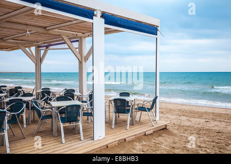 Meer Seite Bar Interieur mit Holzboden und Metall Sessel am Sandstrand Stockfoto