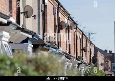 TV-Sat-Anlagen auf Zeile Reihenhäuser - sonnendurchfluteten, Bäume im Vordergrund Stockfoto