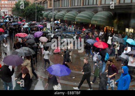 London, UK. 4. Oktober 2014. UK-Wetter. Fußgänger und Shopper Unterschlupf unter Sonnenschirmen draußen gelangten Harrods in Knightsbridge auf einem nassen und regnerischen Tag in London Credit: Amer Ghazzal/Alamy Live-Nachrichten Stockfoto