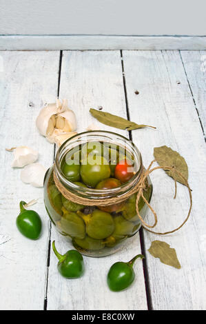 Ein Glas mit frisch gepflückten Chilis in Essig auf einem rustikalen Holztisch erhalten Stockfoto
