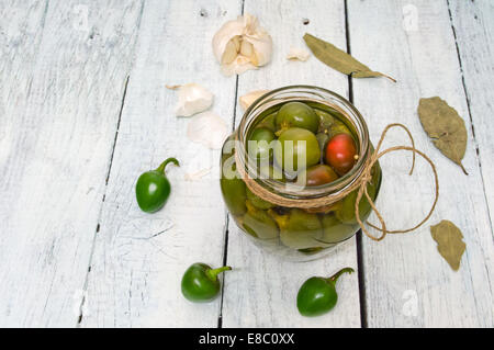 Ein Glas mit frisch gepflückten Chilis in Essig auf einem rustikalen Holztisch erhalten Stockfoto