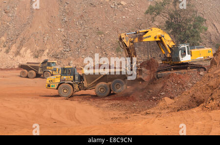Ein kleine Liebherr Bagger lädt einem Glocke Haul Truck während der Bauphase einen Wasserteich Lagerung auf eine Oberfläche afrikanischen Kupfer mine. Stockfoto