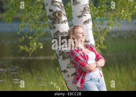 Porträt einer schönen jungen Frau ruht in der Nähe des Sees eine Birke gelehnt Stockfoto