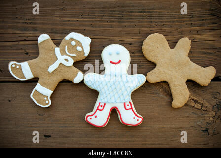 Drei glücklich aussehenden Mann in Ingwer Brot, verschiedene Cookies mit Dekoration oder leer, hölzernen Hintergrund Stockfoto