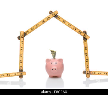 Ein Tischler Herrscher in der Form eines Hauses mit einem Sparschwein unter dem Dach. Querformat auf weiß mit Reflexionen. Wunderbar Stockfoto