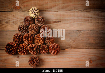 Eine Gruppe von Tannenzapfen in einen Weihnachtsbaum-Form auf einen rustikalen hölzernen Fußboden angeordnet, Horizontal format mit ein Instagram-retro-Look Stockfoto