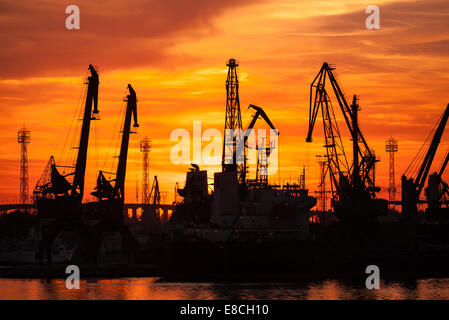 Silhouetten von Kränen und Frachtschiffe im Hafen von Varna bei Sonnenuntergang Stockfoto