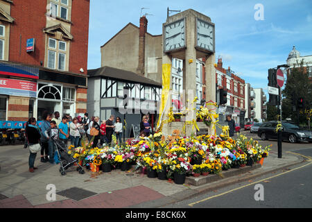 Hanwell, London, UK. 5. Oktober 2014. Menschen stehen, betrachtet man die Blumen gelegt um Hanwell Uhrturm für lokale Schulmädchen Alice Gross, dessen Körper im Fluss Brent, Hanwell, London am 30. September 2014 gefunden wurde. Bildnachweis: Maurice Savage/Alamy Live-Nachrichten Stockfoto