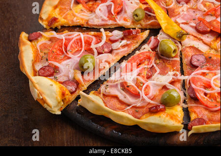 Pizza mit Salami, Peppeeoni, Oliven, Tomaten und gelbe Paprika Stockfoto