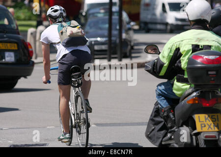 Ein Radfahrer und Motorradfahrer unterwegs entlang einer Straße in London, England Stockfoto