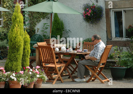 Mann mittleren Alters an Tee Tisch außerhalb Café in Eyam, Derbyshire Stockfoto