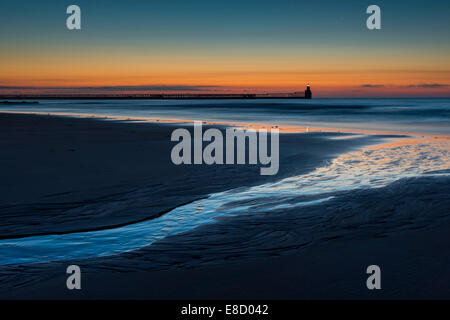 Vom frühen Morgen an Blyth. Linie durch Reflexion am Wasser führt in Richtung Meer, Leuchtturm und dem Pier. Stockfoto