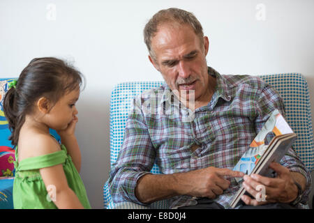 Großeltern, Enkel lesen Stockfoto