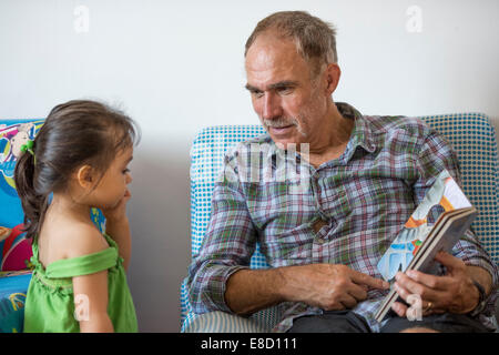 Großeltern, Enkel lesen Stockfoto