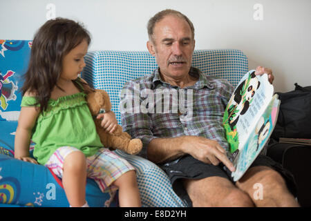 Großeltern, Enkel lesen Stockfoto