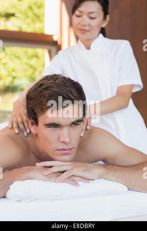 Junger Mann Erhalt Schultermassage im Wellnesscenter Stockfoto