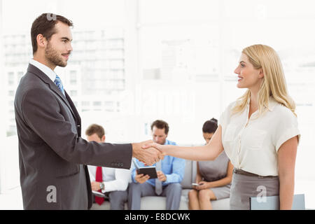 Geschäftsmann Händeschütteln mit Frau neben Menschen warten interview Stockfoto