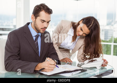 Geschäftsmann und Sekretär betrachten Tagebuch im Büro Stockfoto