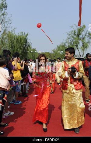 Hangzhou, China Zhejiang Provinz. 6. Oktober 2014. Ein Brautpaar aus Nepal und Pakistan Fuß auf einem roten Teppich während einer Gruppe Hochzeit am Westsee in Hangzhou, Hauptstadt der ostchinesischen Provinz Zhejiang, 6. Oktober 2014. Insgesamt 100 Paare aus 19 Ländern nahmen Teil in einer Gruppe Hochzeit der chinesischen traditionellen Stil in Hangzhou am Montag. © Ju Huanzong/Xinhua/Alamy Live-Nachrichten Stockfoto