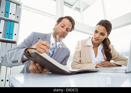 Geschäftsmann und Sekretär betrachten Tagebuch im Büro Stockfoto