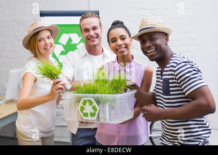 Kreative Business-Team hält Pflanze mit Recyclingsymbol Stockfoto